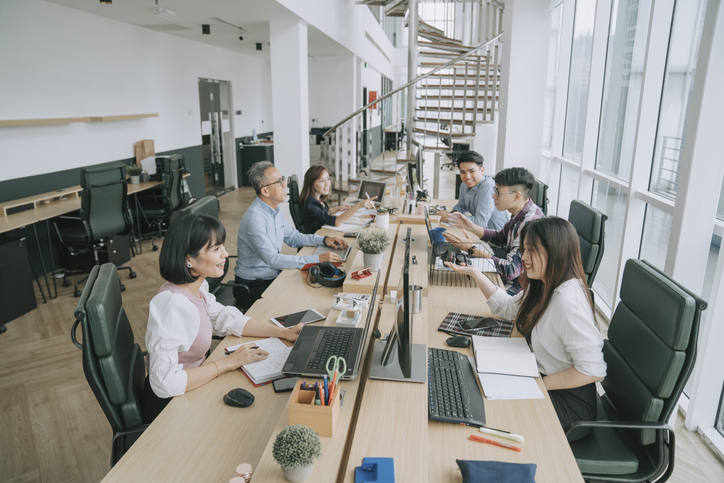 Group of people in a meeting room during the day on their laptops